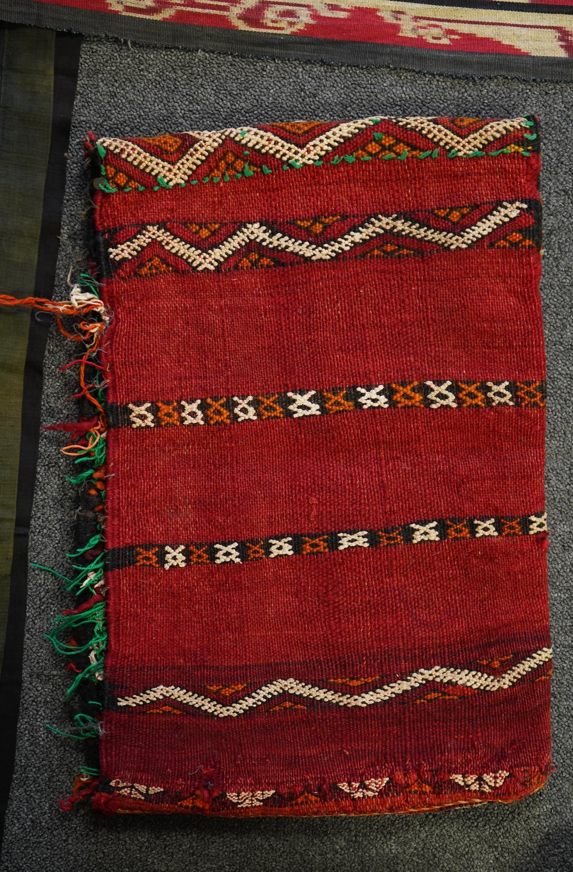 A 20th century Indonesian Sumba single Ikat shoulder cloth, a similar Celebes cloth, a Berber woven skirt and saddle bag and a patchwork cover. (5). Skirt 110cm including hessian top., Condition - some patchwork in the c